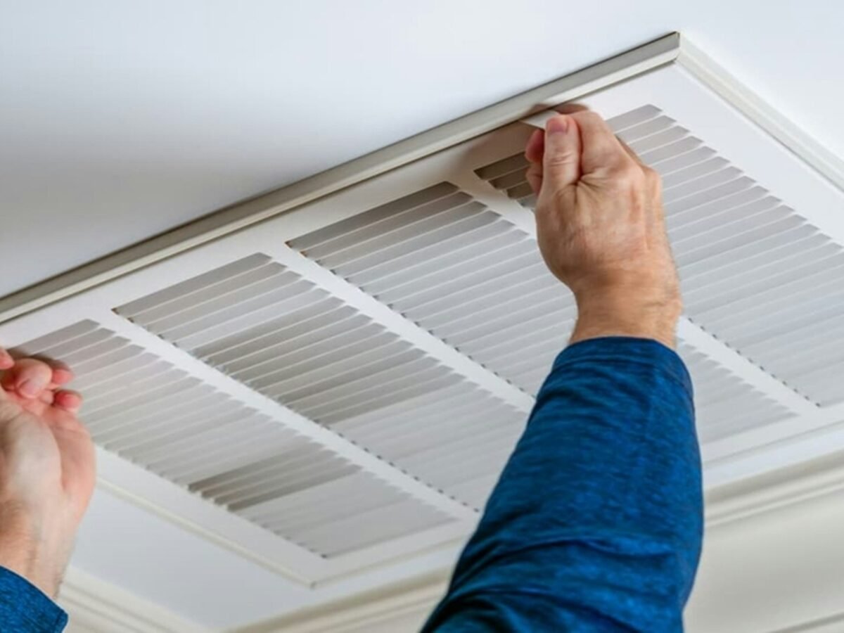 Technicien déposant la grille d’une bouche de climatisation au plafond avant son nettoyage