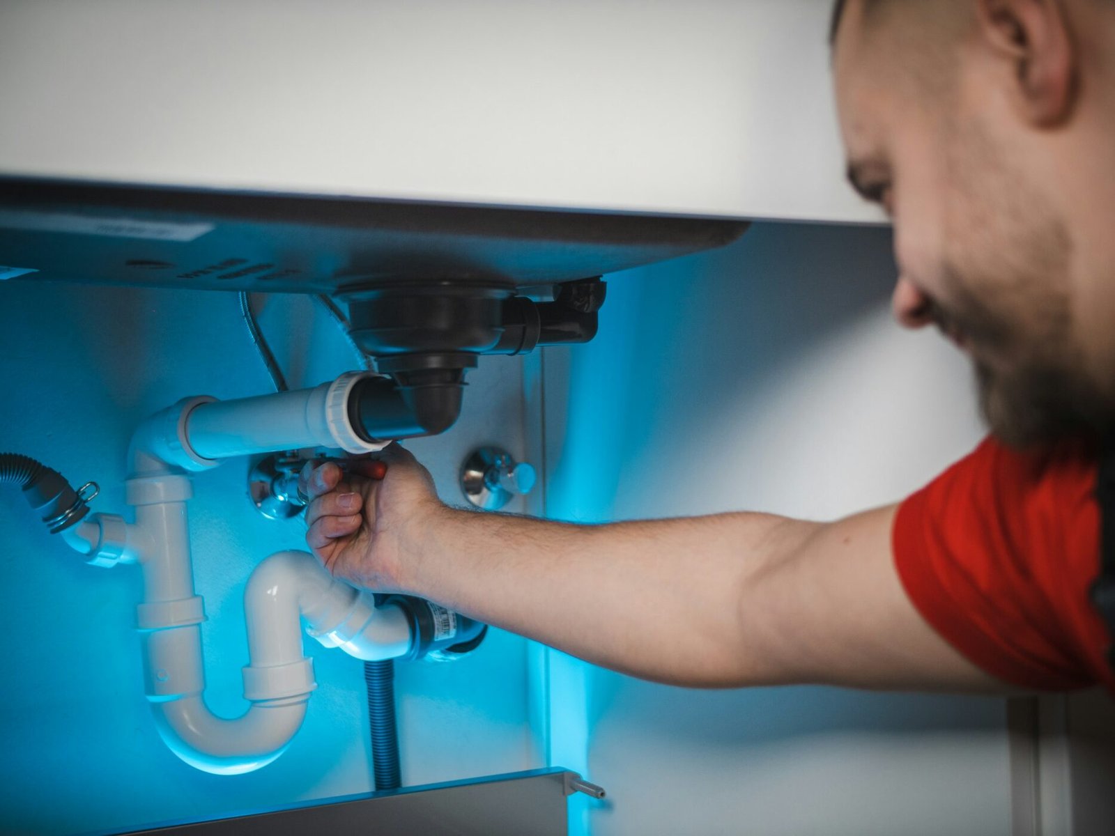 Plombier intervenant sur les raccordements d’évacuation sous un évier